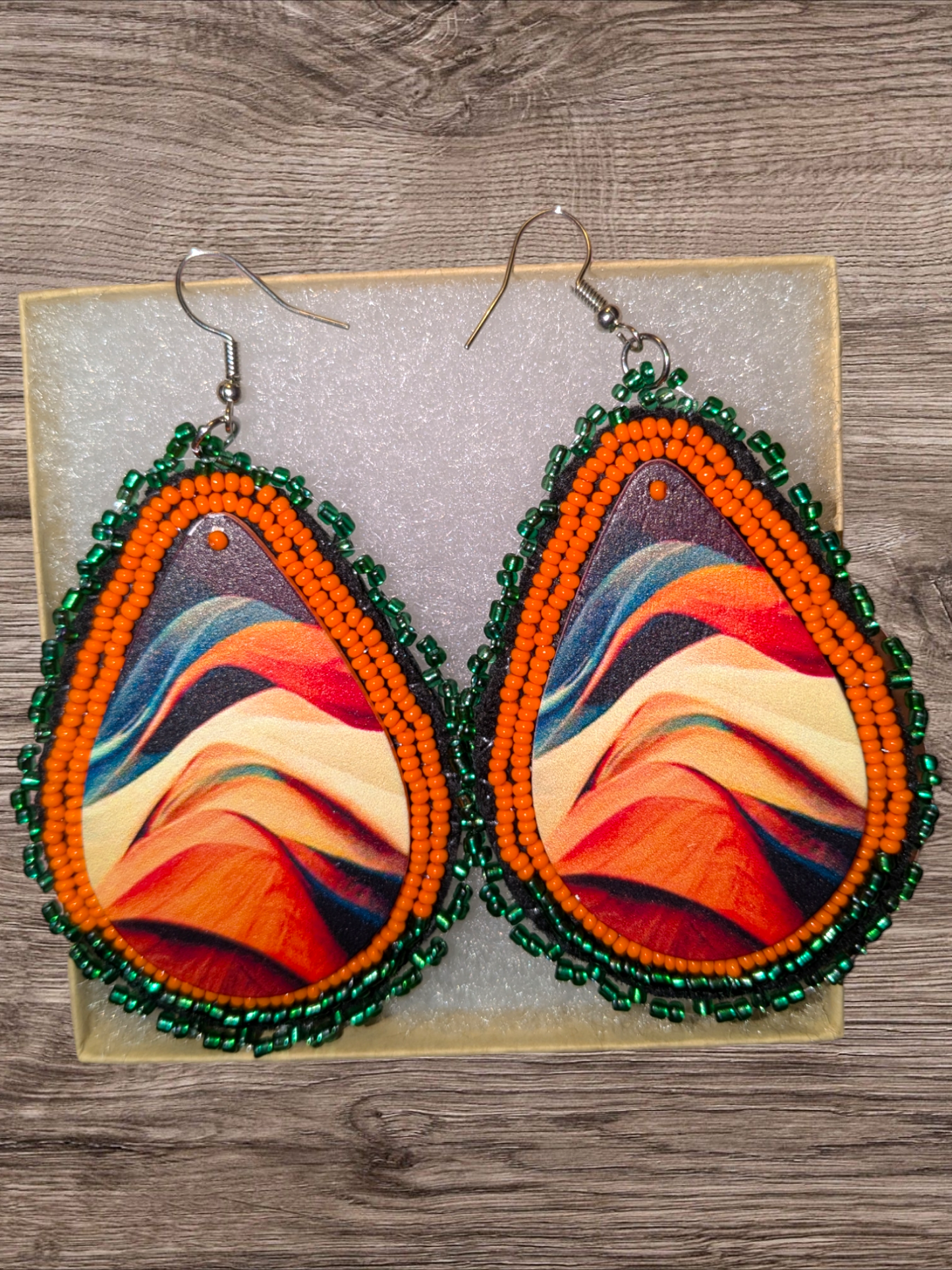 Beaded leather drop earrings with orange and green edging.